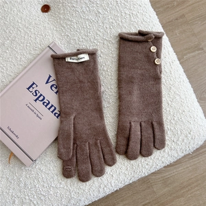 Close-up of coffee brown knitted gloves with vintage wood buttons and woven brand label