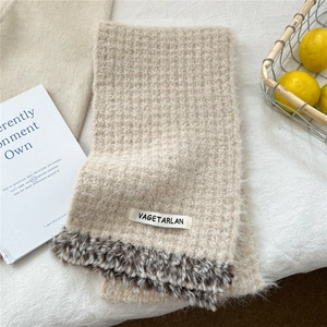 Detail of oatmeal knitted scarf featuring faux fur trim and branded label texture
