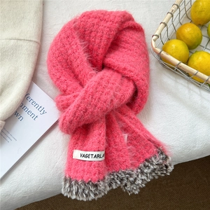 Detail of pink knitted scarf featuring faux fur trim and branded woven label tag