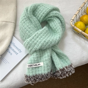 Close-up of mint green knitted scarf with brown faux fur trim and branded fabric label