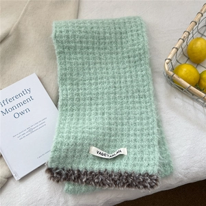 Detail of mint green waffle knit scarf with brown faux fur trim and woven label detail