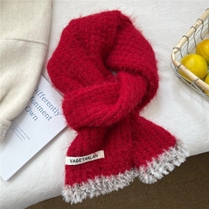 Detail of red knit scarf with faux fur trim and branded label on white background