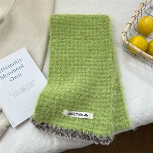 Detail of green knit scarf featuring leopard print faux fur trim and branded label