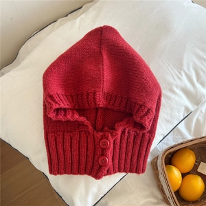 Dettaglio del cappuccio passamontagna rosso in maglia grossa con chiusure a bottoni