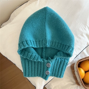 Dettaglio della sciarpa con cappuccio in maglia verde petrolio e bottoni