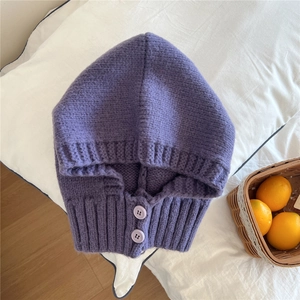 Dettaglio di un passamontagna in maglia viola con texture spessa e chiusura a bottoni
