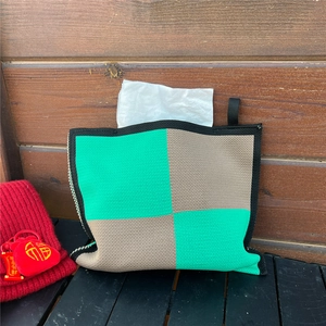 Detail of green and beige checkered knit tissue cover with festive red ornaments on a desk