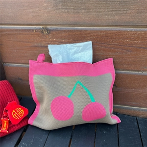 Detail of knitted tissue cover with pink cherry pattern and convenient hanging loop