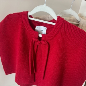 Detail of red knitted shawl scarf showing the knotted neck design and premium soft texture