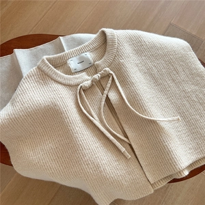 Detail of oat-beige ribbed knit shawl featuring a knotted tie and premium inner brand tag
