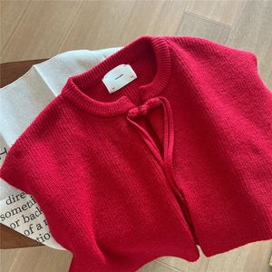 Detail of red knit shawl collar with manual knot tie on warm winter sweater wrap