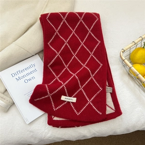Gros plan d'une écharpe 100% laine à carreaux rouges avec texture tricotée et étiquette