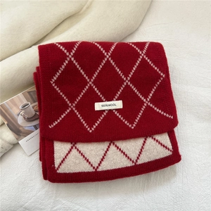 Détail de l'écharpe en laine à motif de losanges rouges et beige montrant l'étiquette 100% laine
