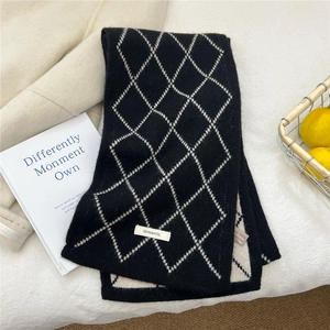 Détail de l'étiquette 100 % laine sur une écharpe en tricot à carreaux noirs et blancs