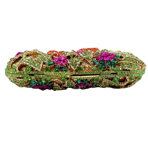 Détail d'une pochette de soirée florale ajourée avec strass colorés et cadre doré