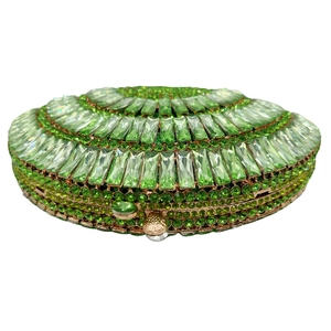 Macro shot of emerald crystal hollow evening clutch with gold metal frame and jewel lock