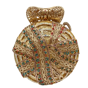 Macro shot of circular gold evening bag with rhinestones and hollow metal handle detail