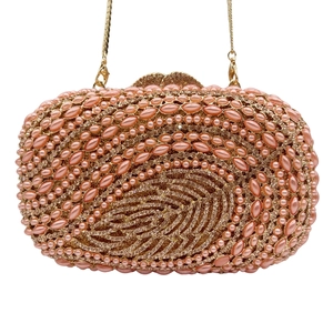 Detailed shot of pink pearls and leaf-shaped crystal pattern on luxury evening clutch bag
