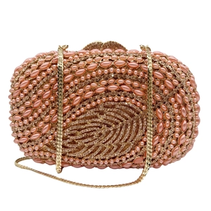 Detailed close-up of champagne gold evening clutch with hollow leaf design and pearls