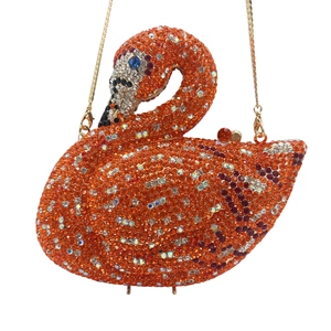 Macro shot of swan evening bag with vibrant orange and red crystals and a gold chain
