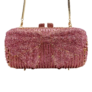 Detail of hot pink rhinestone evening bag with oversized bow and gold chain strap