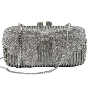 Close-up of sparkling silver rhinestone evening clutch with large bow and metal chain