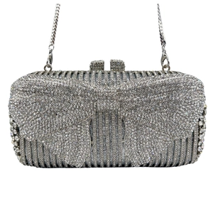 Detailed close-up of a silver evening clutch bag with sparkling bow and rhinestones