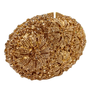 Detailed close-up of champagne crystal floral pattern on an oval metal evening clutch bag