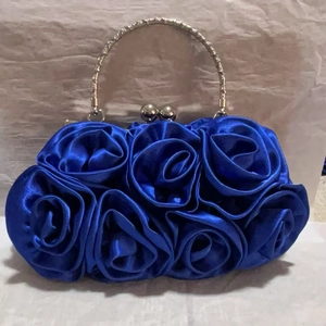 Detail of royal blue satin evening bag featuring 3D handmade silk rose flowers and metal handle