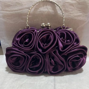 Detail of purple satin clutch bag featuring handmade 3D rose petals and metal ring handle