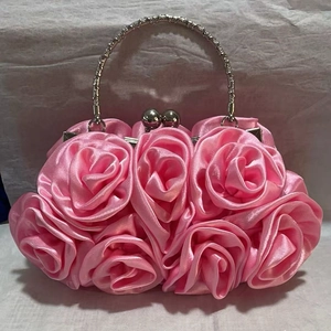 Close-up of pink satin clutch featuring 3D rose flower textures and silver metal handle