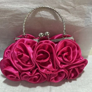Detail of rose red satin flower clutch bag with diamond-encrusted metal handle and spherical lock