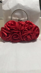 Detail of red satin evening clutch bag featuring handmade 3D rose flower design