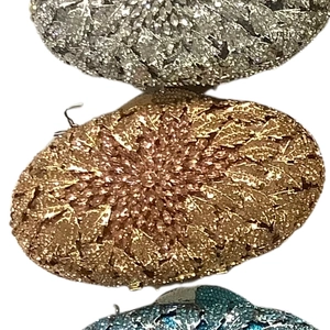 Detail view of oval evening bags in silver, gold, and blue with leaf textured metal finish