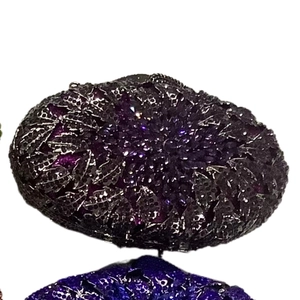 Macro shot of purple crystal-studded leaf pattern on luxury metal evening clutch bag