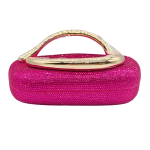 Détail d'une pochette de soirée rose rouge avec strass brillants et poignée en métal doré