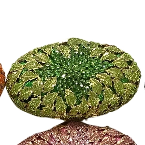 Detail of a green oval crystal evening bag featuring a radiant leaf-shaped rhinestone design