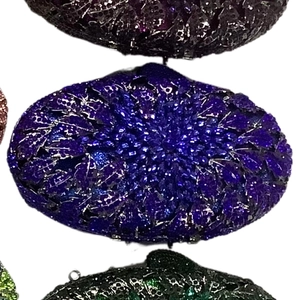 Detailed macro view of an oval evening clutch bag with sparkling purple and blue crystals