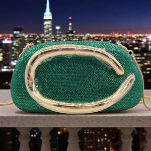 Detail of emerald green rhinestone clutch with a bold golden C-shaped metal handle
