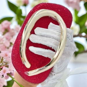 Macro shot of red rhinestone clutch bag held with white lace gloves in cherry blossoms