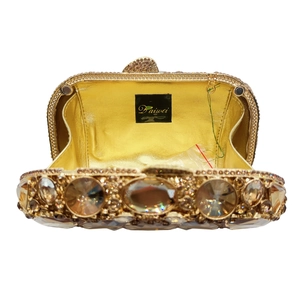 Interior detail of golden stone clutch bag showing rhinestone patterns and magnetic clasp