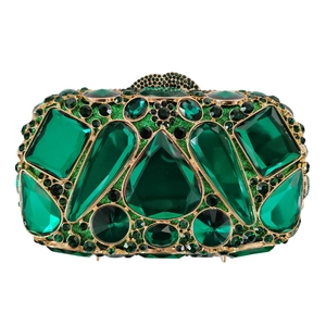 Macro shot of emerald gemstones and black diamonds on a luxury gold evening clutch bag