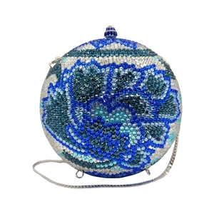 Macro detail of hand-set crystal flowers on a sphere evening bag with silver chain