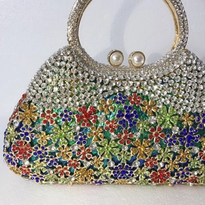 Détail d'une pochette de soirée aux fleurs de cristaux colorés avec poignée dorée et perles