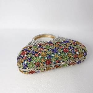 Détail macro du motif floral en strass colorés sur une pochette de soirée en métal