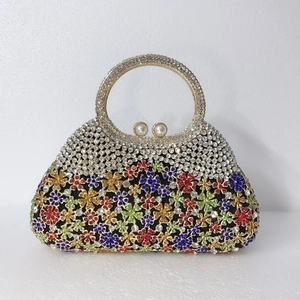 Détail d'une pochette de soirée avec fleurs en strass colorées et fermoir en perles