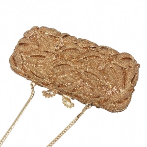Detailed shot of golden lip clutch featuring woven leaf patterns and sparkling rhinestones