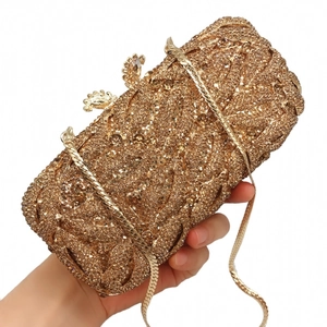 Macro detail of luxury gold hollow-out clutch with sparkling crystals and metal chain
