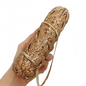 Detail of luxury gold cylindrical clutch bag with shimmering crystals and chain strap