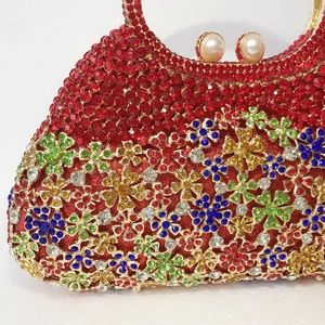 Gros plan d'une pochette rouge en strass avec fleurs en cristal et fermoir en perles